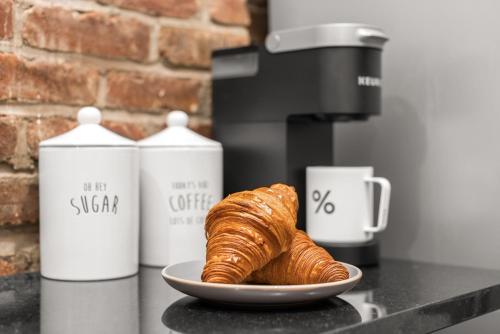 a plate of croissants on a counter next to two coffee makers at Stylish Escape Modern 2BR Condo on Prince Street in New York