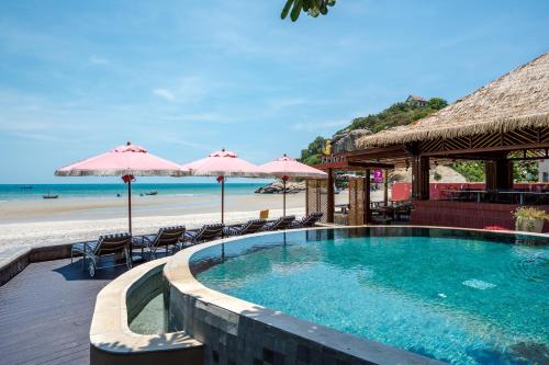 a swimming pool next to a beach with umbrellas at Davinia Hua Hin Resort in Hua Hin