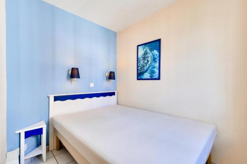 Ce lit se trouve dans un dortoir aux murs bleus. dans l'établissement Résidence Port Bourgenay - maeva Home - 2 Pièces 5 Personnes Sélection MAE-2093, à Talmont-Saint-Hilaire