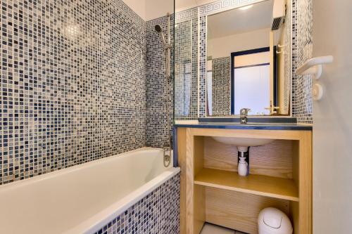 une salle de bain avec un lavabo, une baignoire et un miroir dans l'établissement Résidence Port Bourgenay - maeva Home - 2 Pièces 5 Personnes Sélection MAE-2093, à Talmont-Saint-Hilaire