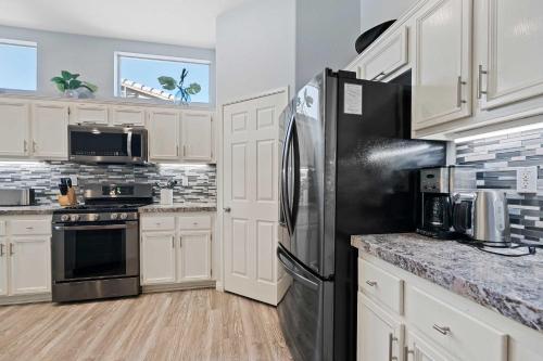 a kitchen with white cabinets and a black refrigerator at Antigua Villa - Volleyball - Pool - 5Bd in Indio