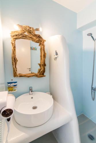 a bathroom with a white sink and a mirror at Fratelli Family Rooms in Tinos Town
