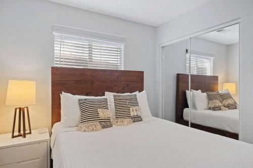 a white bedroom with a bed and a mirror at Antigua Villa - Volleyball - Pool - 5Bd in Indio