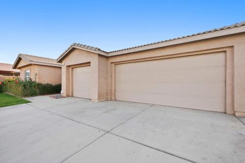 a house with two garage doors in a driveway at Antigua Villa - Volleyball - Pool - 5Bd in Indio