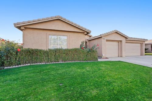 a house with a green lawn in front of a house at Antigua Villa - Volleyball - Pool - 5Bd in Indio