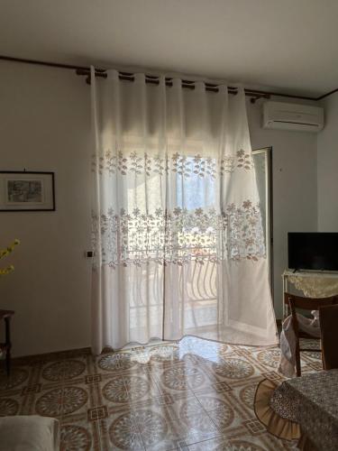 a white curtain in a room with a window at Casa Puglia in Giardini Naxos