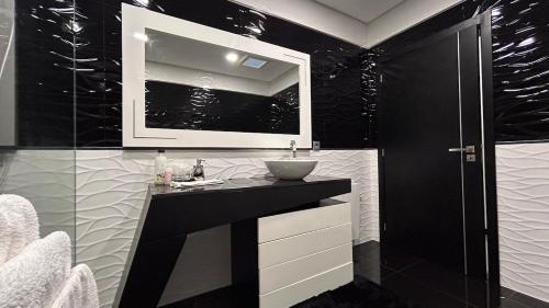 a black and white bathroom with a sink and a mirror at Home S&F- Ponte de Vagos in Ponte de Vagos