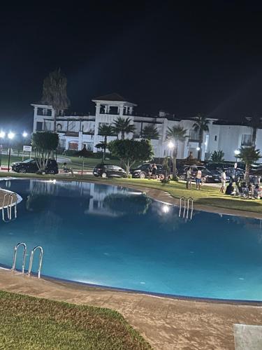 a large swimming pool in front of a building at night at Appartement pied dans l eau à Residence Beralmar in Asilah