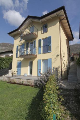 a large yellow house with a balcony and a yard at Maison Mimi apartments in Ossuccio