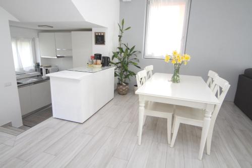 a kitchen and dining room with a white table and chairs at Maison Mimi apartments in Ossuccio