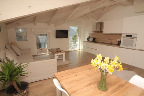 a kitchen and living room with a table and yellow flowers at Maison Mimi apartments in Ossuccio