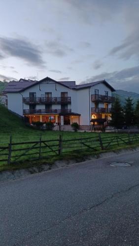 a large white house with a fence in front of it at Pensiunea Bike&Bed in Moieciu de Jos