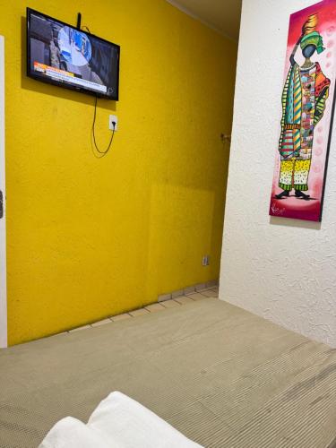 a yellow room with a tv on a yellow wall at Pousada Cores do Pelô in Salvador