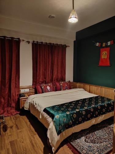 a bedroom with a large bed with red curtains at Flugafen B&B- A Peaceful home in Apple Orchards in Manāli