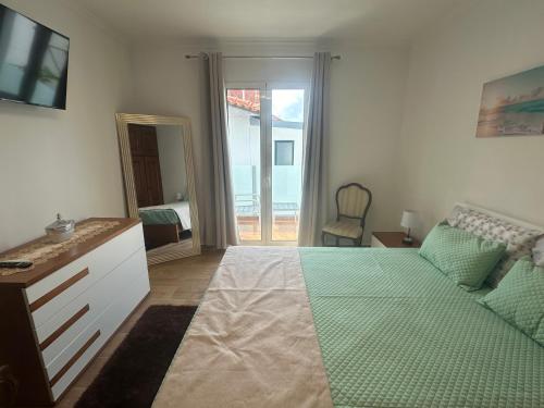 a bedroom with a bed and a couch and a television at Gori House in Madalena do Mar