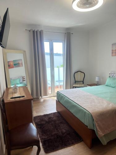 a bedroom with a bed and a desk and a window at Gori House in Madalena do Mar