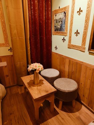 a living room with two chairs and a table with flowers at Flugafen B&B- A Peaceful home in Apple Orchards in Manāli
