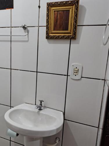 a bathroom with a sink and a picture on the wall at Casinha central Manhuaçu in Manhuaçu