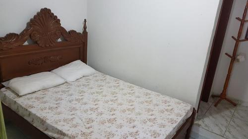 Una cama pequeña en una habitación con una pared blanca. en Duplex dos Anjos, en Arraial do Cabo