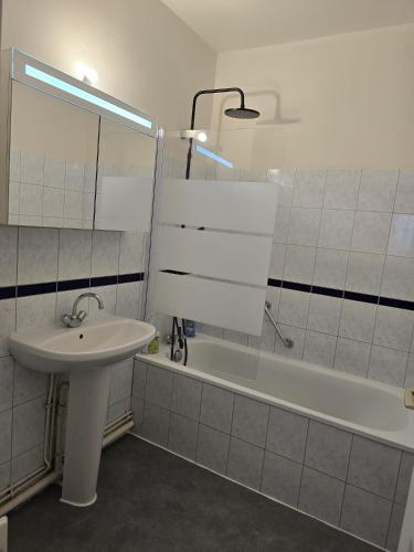 une salle de bain blanche avec un lavabo et une baignoire dans l'établissement T3 Tout Confort, à Bagnoles-de-l'Orne