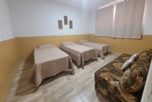 a room with three beds and a couch in it at Apto na Rua Principal - Centro in Serra Negra