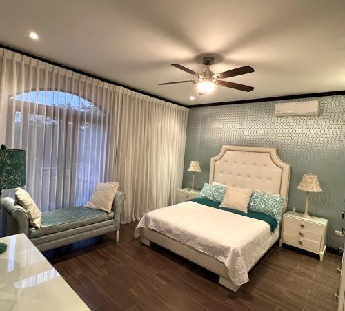 a bedroom with a bed and a chair and a ceiling fan at Wonderful House in Piedades
