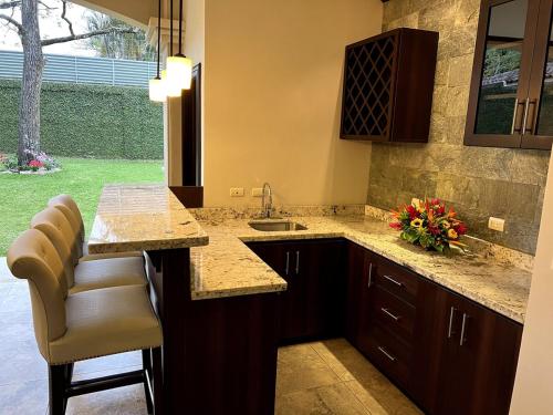a kitchen with a sink and a counter with chairs at Wonderful House in Piedades