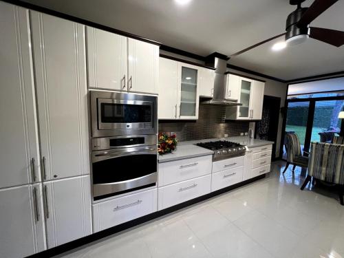 a kitchen with white cabinets and stainless steel appliances at Wonderful House in Piedades