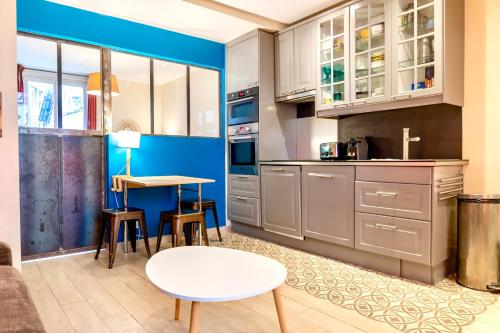 une cuisine avec des armoires blanches et une table et des chaises dans l'établissement LE GABRIEL - Charmant 2 pièces aux portes de Paris, à Malakoff