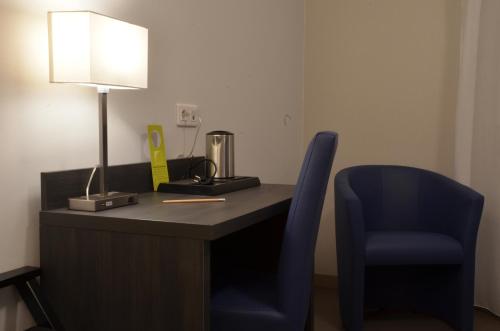 a desk with a lamp and a blue chair at Logis Hôtel - La Chambre d'Amiens in Amiens