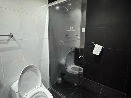 a bathroom with a toilet and a glass shower door at Gaviota Apartments & Suites in Cuenca