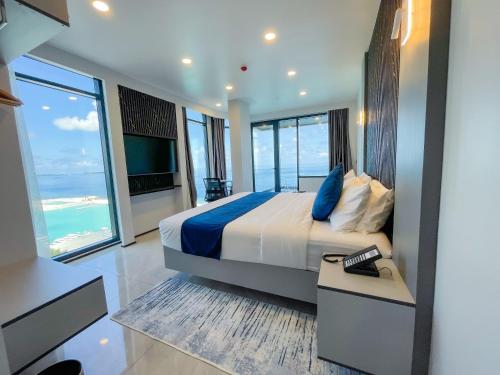 a bedroom with a bed with blue pillows and a television at iCom Blue Seaview in Maafushi