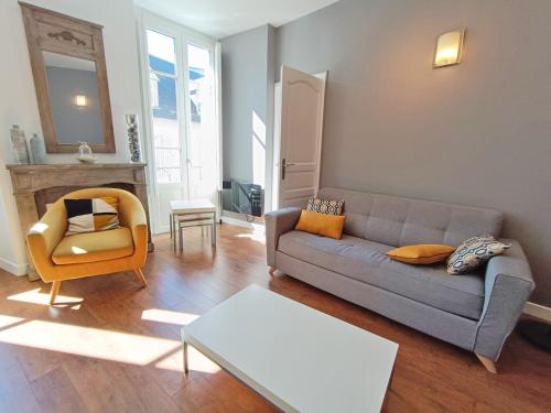una sala de estar con un sofá y una silla en Luchon Holidays, parking, wifi, balcon, cave, T3 8 personnes, en Luchon