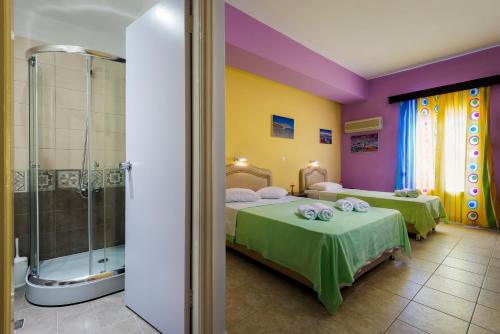 a room with two beds and a shower at Elefteria Hotel in Agia Marina
