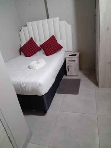 a white bed with red pillows in a room at Arrival Center BnB in Maseru