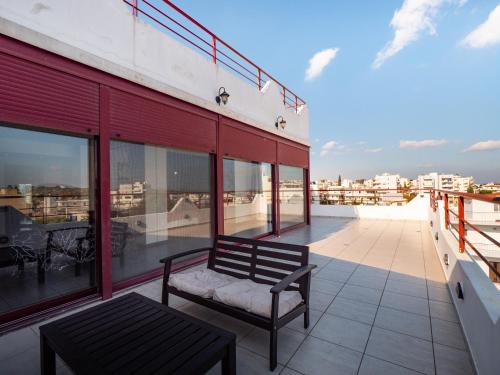 a bench sitting on the balcony of a building at 5-Star feel - Luxury penthouse for 4 with huge balcony & view ,8 min from Athens airport in Koropíon