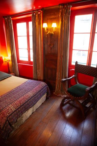 une chambre avec un lit, une chaise et des fenêtres dans l'établissement Le Marais Chic AC, à Paris