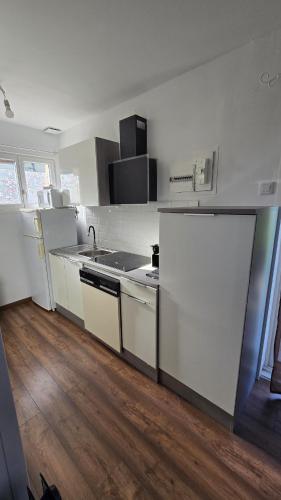 une cuisine avec des appareils blancs et un parquet dans l'établissement Maison de ville, à Pontonx-sur-lʼAdour