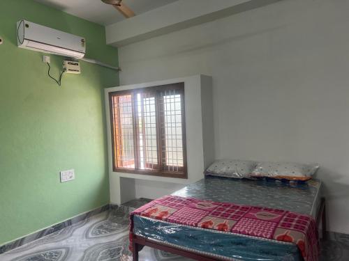 a bedroom with a bed in a room with a window at Tej Home Stays and Guest House in Miriālgūda