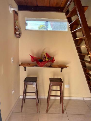 einen Tisch und zwei Hocker in einem Zimmer mit einer Treppe in der Unterkunft Chalé aconchegante in Cabo de Santo Agostinho