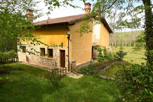 a small yellow house in a field of grass at La Palombrera in Treceño