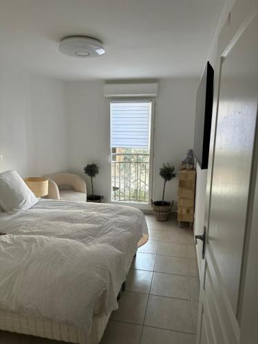une chambre blanche avec un lit et une fenêtre dans l'établissement duplex design, calme, au vallon des auffes, bord de mer, à Marseille