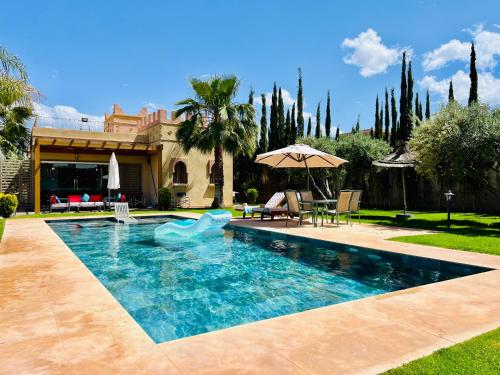 a swimming pool with a blue dolphin in a yard at Villa privée avec piscine pour familles à Marrakech, Lalla Takerkousst in Marrakech
