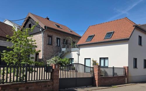 a white house with a black fence next to two buildings at L'atelier - logement neuf sur la route des vins d'Alsace in Voegtlinshoffen