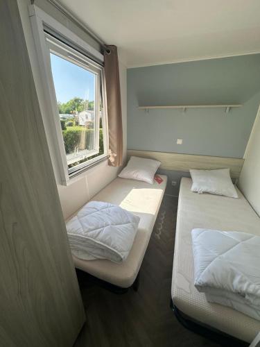 deux lits dans une petite pièce avec une fenêtre dans l'établissement La Palmyre - Les Mathes - Nouveau Mobil home - Camping 4 étoiles 