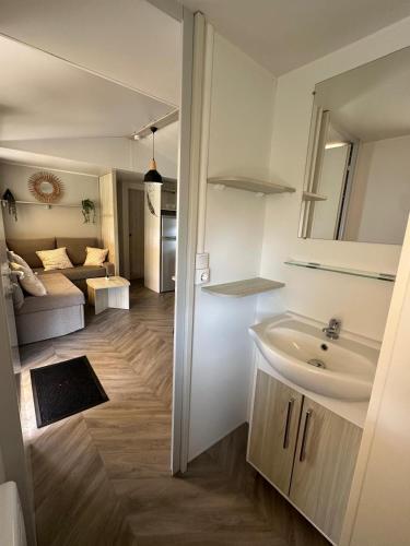 une salle de bain avec lavabo et un salon dans l'établissement La Palmyre - Les Mathes - Nouveau Mobil home - Camping 4 étoiles 