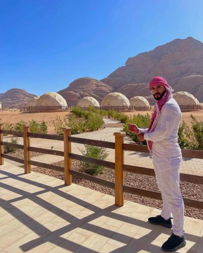 a man standing next to a fence in the desert at Talal Rum Luxury Camp in Jurf ad Darāwīsh