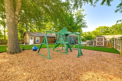 a playground with a green swing set next to a tree at Home with Hot Tub, Playset and Grills in Clarksville! in Clarksville