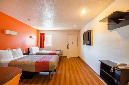 a hotel room with two beds and a television at Economy Hotel Kansas City in Blue Springs
