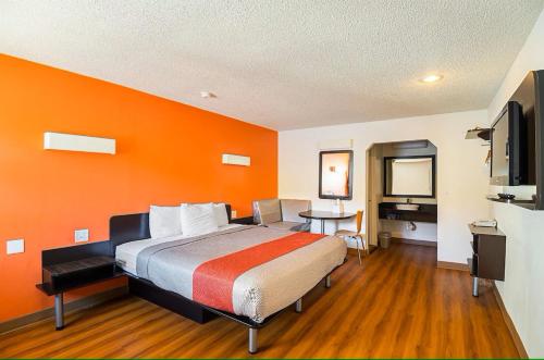 a hotel room with a bed with an orange wall at Economy Hotel Kansas City in Blue Springs